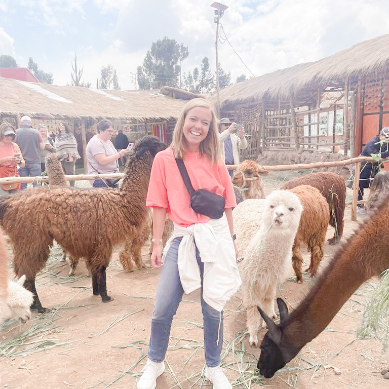 A Briar & Main travel agent posing in front of a llama farm on Adventures by Disney Peru